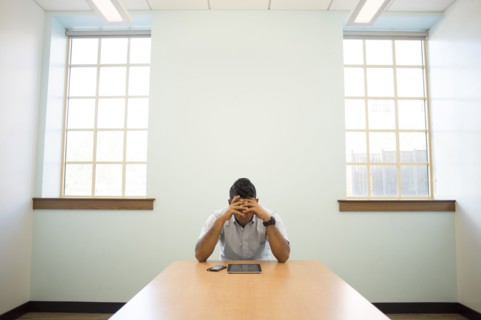 Frustrated Asian businessman using digital tablet in office