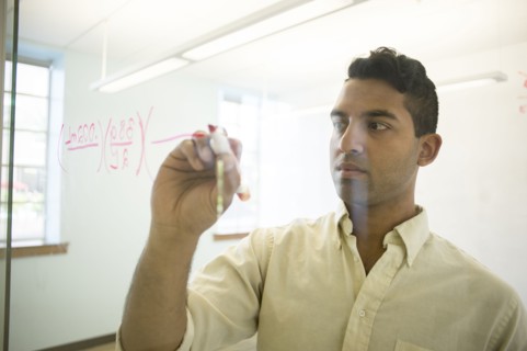 Asian businessman writing on glass window in office