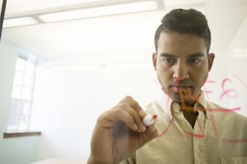 Asian businessman writing on glass window in office