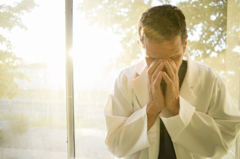 Stressed Hispanic doctor rubbing his eyes
