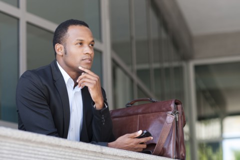 Black businessman thinking outside building