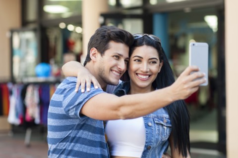 Hispanic couple taking selfie outdoors
