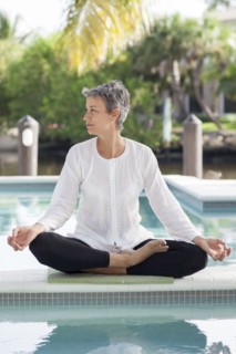 Woman meditating by still swimming pool
