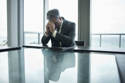 Caucasian businessman holding head in hands at conference table