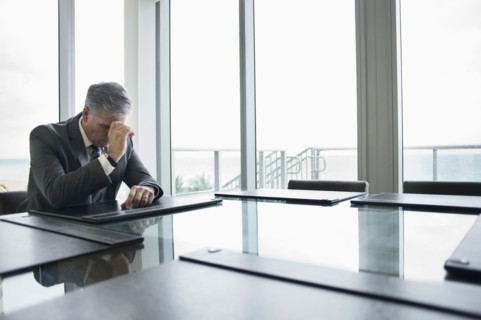 Caucasian businessman brooding at empty conference table