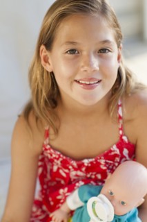 Close up of Caucasian girl holding baby doll