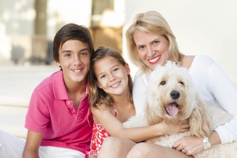 Smiling mother and children posing with dog outdoors