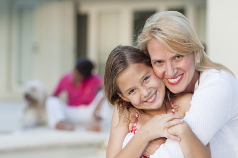 Smiling mother and daughter hugging outdoors