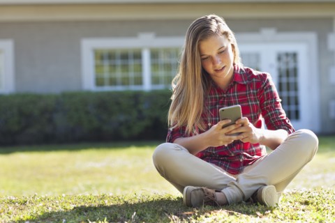 Caucasian girl using cell phone in backyard