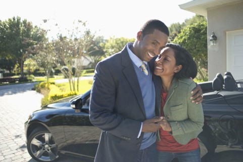 Couple hugging in driveway at convertible