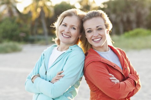 Caucasian mother and daughter standing on beach