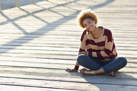 Black woman sitting on wooden boardwalk
