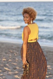Black woman carrying sandals on beach