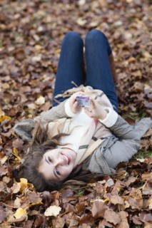 Hispanic girl laying in autumn leaves