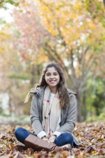 Hispanic girl sitting in autumn leaves