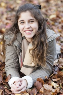 Hispanic girl laying in autumn leaves