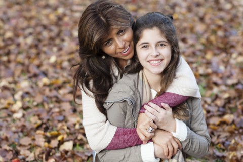 Hispanic mother and daughter hugging in autumn leaves