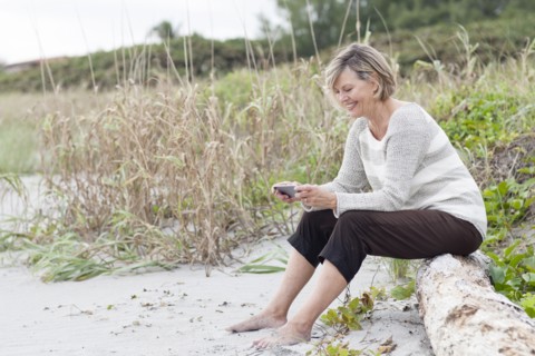 Caucasian woman using cell phone on beach