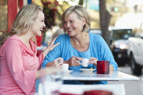 Caucasian mother and daughter drinking coffee at sidewalk cafe