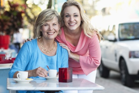 Caucasian mother and daughter drinking coffee at sidewalk cafe