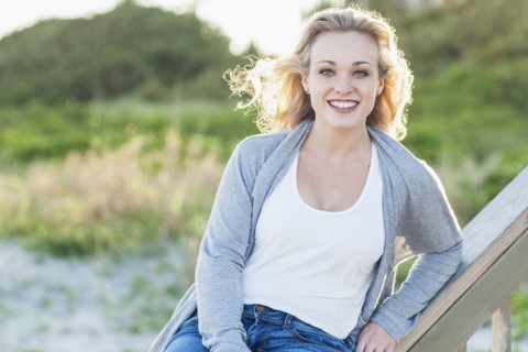 Smiling Caucasian woman sitting on banister over beach