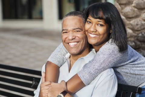 African American father and daughter hugging on bench