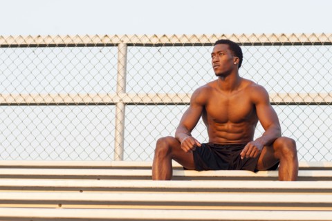 Serious Black athlete siting on bleachers