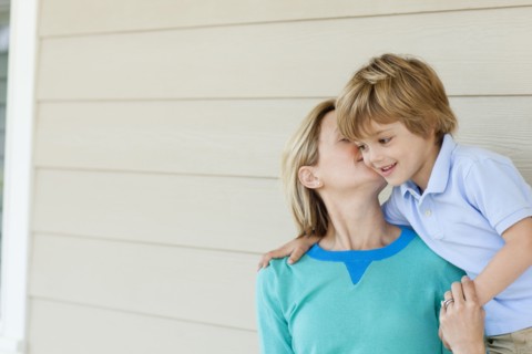 Caucasian mother kissing son on patio