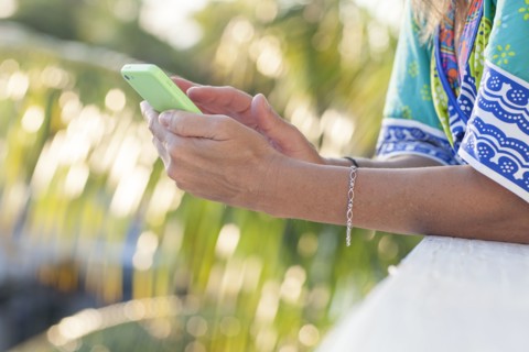 Hispanic woman using cell phone outdoors