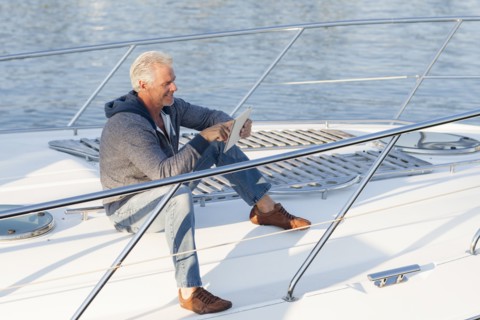 Caucasian man using digital tablet on sailboat deck