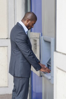 Black businessman using ATM in city