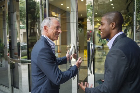 Businessman opening office door for colleague