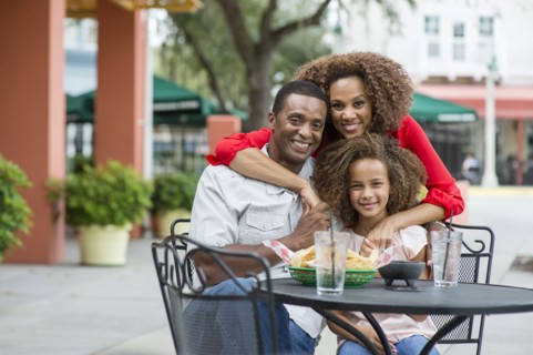 Family smiling at outdoor restaurant table