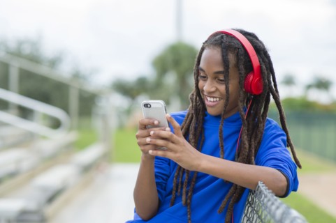 Mixed race boy using cell phone on bleachers