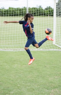 Mixed race boy kicking soccer ball on field