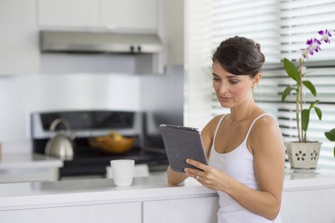 Caucasian woman using digital tablet in kitchen