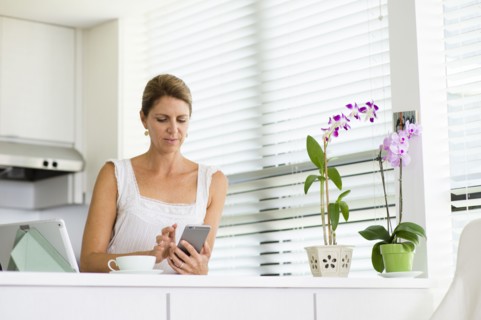 Caucasian woman using cell phone in kitchen
