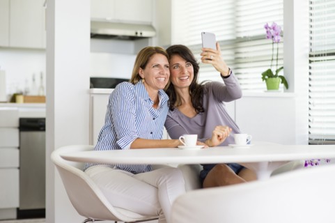 Caucasian women taking selfie in kitchen