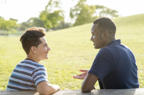 Father and son talking at table in park