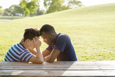 Father and son talking at table in park