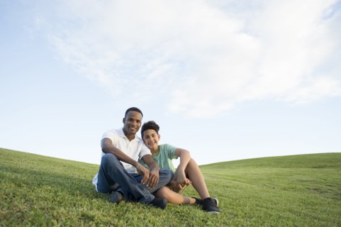 Father and son sitting in grass