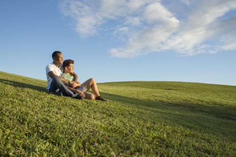 Father and son sitting in grass