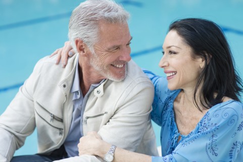 Caucasian couple hugging poolside