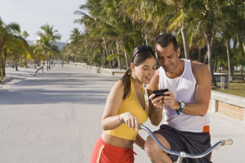 Hispanic couple on bicycles looking at cell phone
