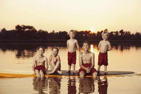 Caucasian children sitting on paddleboard