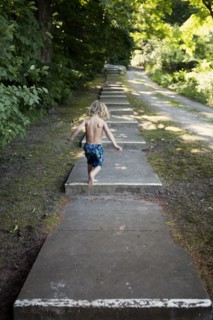Caucasian boy climbing stairs near rural path