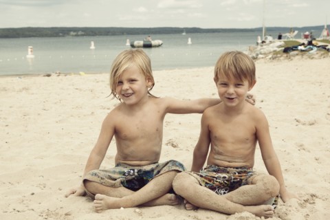 Caucasian brothers hugging on beach