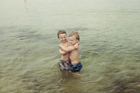 Caucasian boys hugging in lake