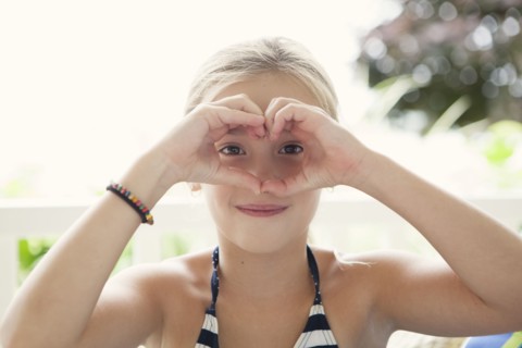 Caucasian girl making heart shape around eyes