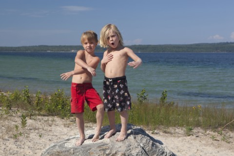 Caucasian boys standing on rock at beach
